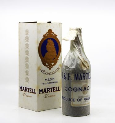 une vieille bouteille de vin posée à côté d'une boîte sur une surface blanche