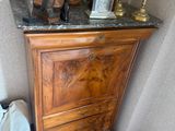 une armoire en bois avec un plateau en marbre, sur laquelle est posé un vase en métal