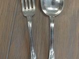 two silver spoons and a fork on a wooden table