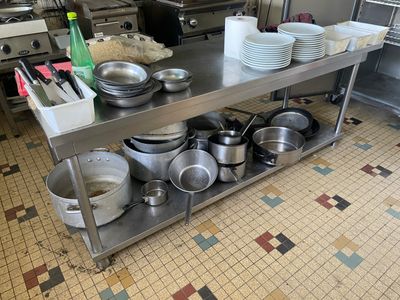 de nombreuses casseroles et poêles posées sur une table en acier inoxydable