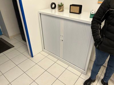 une femme debout dans une salle de bains, à côté d'une armoire