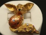 a gold colored animal brooch with colorful stones on it
