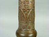 a close up of a brass vase on a table