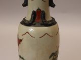 a white vase with a painting on it sitting on a table
