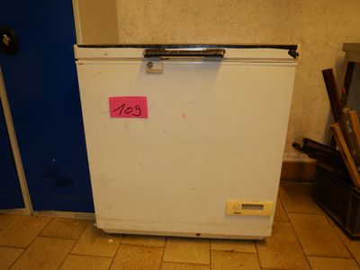 a small white refrigerator with a pink sticker on it