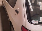 a white car parked in a garage with a truck in the background
