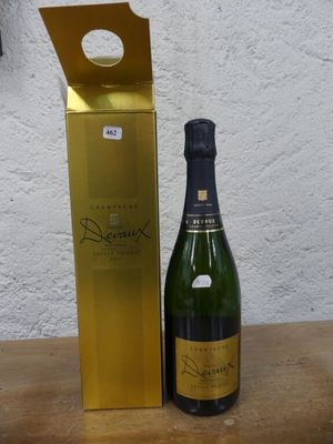 une bouteille de champagne posée à côté d'un coffret en or sur une table en bois