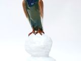 a figurine of a bird sitting on top of a pile of snow