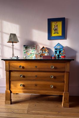 a dresser in the corner of a room with a lamp on it