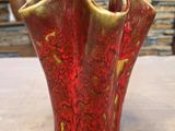 un vase rouge et doré posé sur une table devant un mur de pierre
