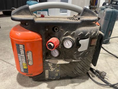 un compresseur d'air orange et noir posé sur un sol en béton