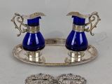 une paire de vases en verre bleu posés sur un plateau en argent, accompagnés d'une paire de broches