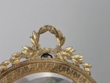 a mirror with a gold frame and a clock on it