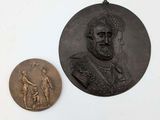 deux médaillons en bronze représentant un homme et une femme sur un fond blanc