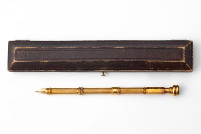 an old pen and a wooden box on a white surface