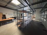 a room with a desk, shelves, and a chair in it