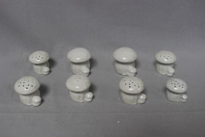 a lot of small white ceramic mushrooms on a table