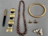 un collier, un bracelet, un stylo et d'autres objets posés sur une table
