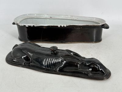 une figurine de chat noir posée à côté d'un plateau en métal