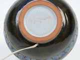 a black and blue vase with a brown rim on a white surface
