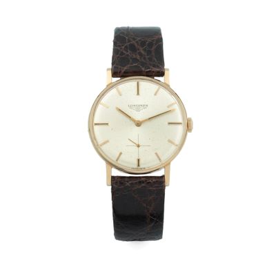 gros plan d'une montre sur une surface blanche avec un bracelet marron