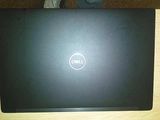 dell laptop computer sitting on a wooden table with a person standing in front of it