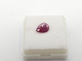 a close up of a red ruby stone on a white surface