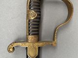 a close up of a sword with a gold handle on a white surface