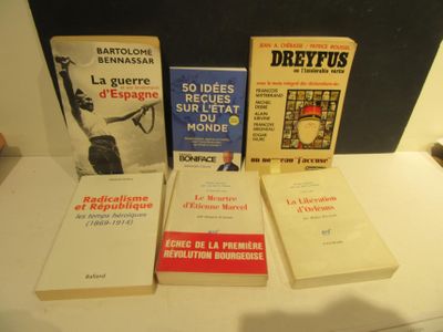 Plusieurs livres sont posés sur une table devant un tableau noir.