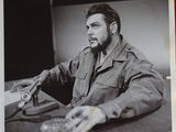 photographie en noir et blanc d'un homme assis à une table avec un appareil photo