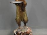 une statue représentant un écureuil tenant une assiette sur un rocher