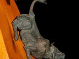 a statue of a bull and a pine cone on a wooden stand