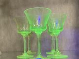 trois verres à vin verts posés sur une table en verre