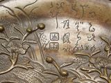 a close up of a metal plate with a bird and flowers on it