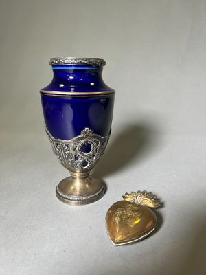 a blue vase and a gold heart on a white table