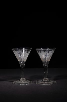 two empty wine glasses sitting on a table with a black background