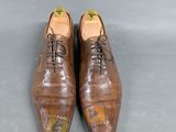 pair of men ' s brown leather shoes on a grey surface