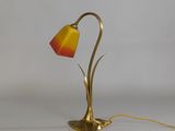 brass table lamp with a red and yellow shade on a white background
