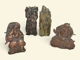 trois figurines en bronze représentant des personnes assises sur une surface blanche