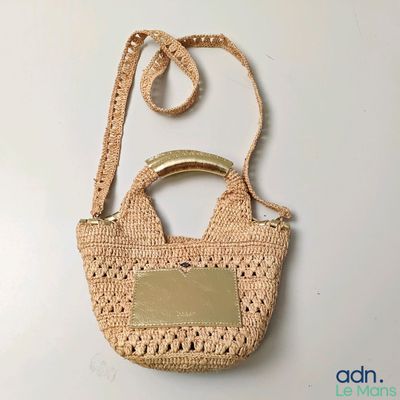 sac à main beige au crochet, muni d'une poignée et d'une étiquette en métal
