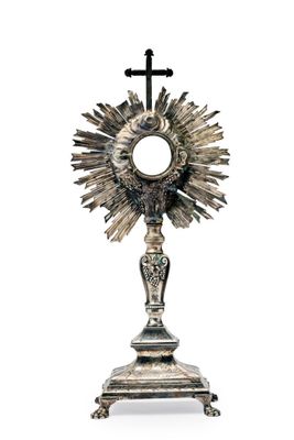 une image représentant une statue en argent représentant un soleil surmonté d'une croix