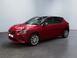 Une voiture rouge est garée dans une pièce aux murs blancs