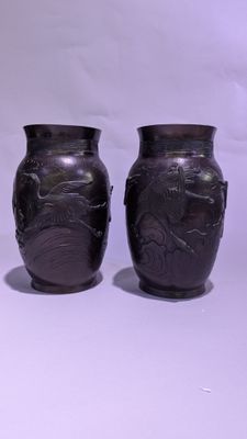 deux vases noirs posés l'un à côté de l'autre sur une surface blanche