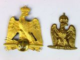 deux insignes représentant un aigle doré sur fond blanc, l'un surmonté d'une couronne et l'autre surmonté d'une couronne