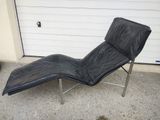 une photo d'une chaise longue en cuir noir devant un garage