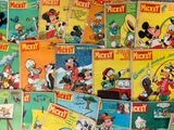 mickey mouse comics are stacked on top of each other on a table