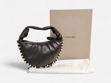 Le sac à main en cuir noir se trouve à côté d'une boîte et d'un tissu blanc