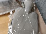 une bouillotte dans un sac en plastique posée par terre