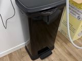 une poubelle noire posée par terre à côté d'un téléphone