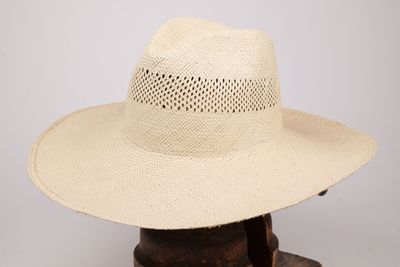 une image représentant un chapeau de paille posé sur un support en bois, sur fond blanc